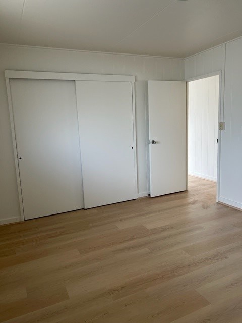 Three white doors in a room with wooden floors.